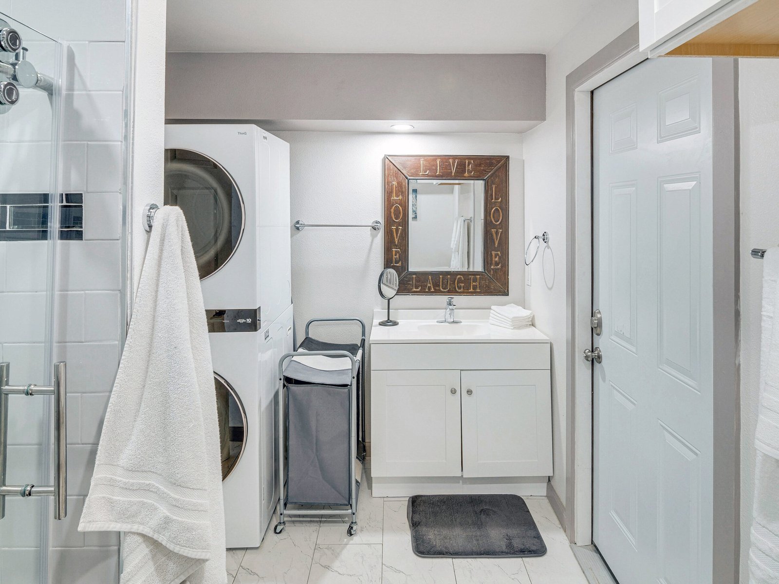 Newbury Park Vacation Rental | The Surf Retreat Modern 1BR 12 Bright and modern open-concept living room and kitchen space with cozy gray sectional, flat-screen TV, and fully equipped white kitchen – perfect for long-term or short-term rentals, sober living homes, and military housing.